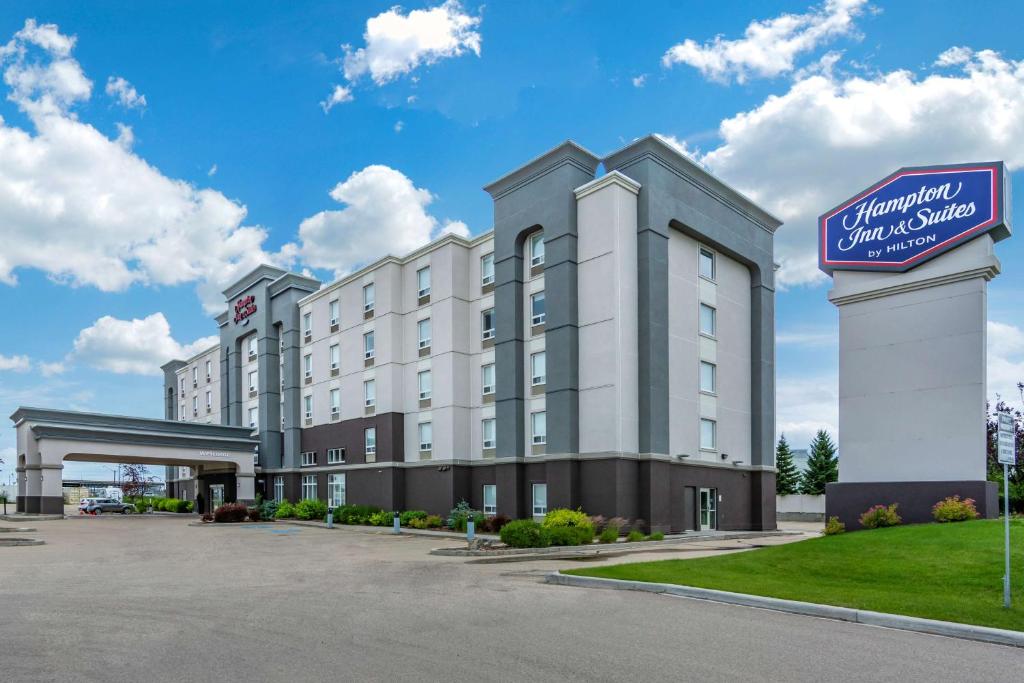 un hôtel avec un panneau en face d'un parking dans l'établissement Hampton Inn & Suites Edmonton/West, à Edmonton