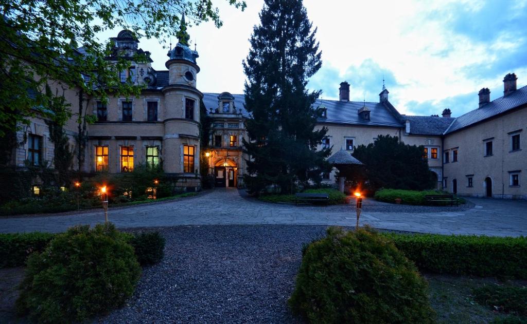 Historic castle courtyard at dusk, illuminated windows, surrounded by trees.