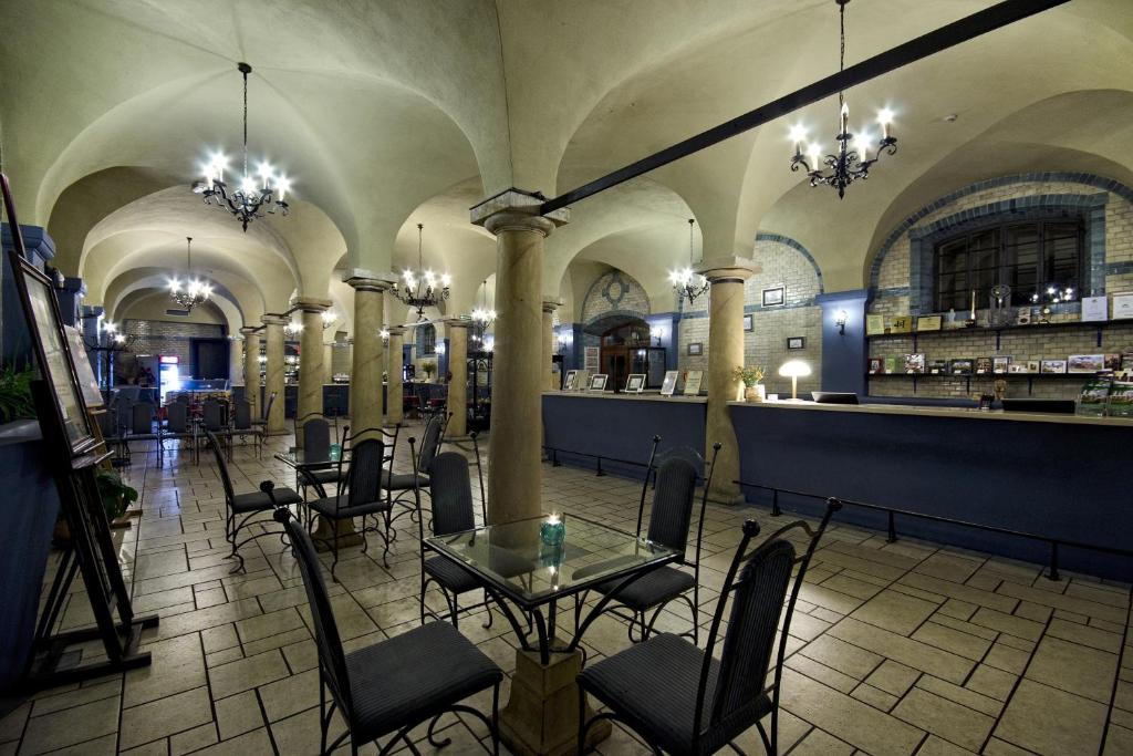 Spacious dining area with arched ceilings, chandeliers, and tables with chairs.
