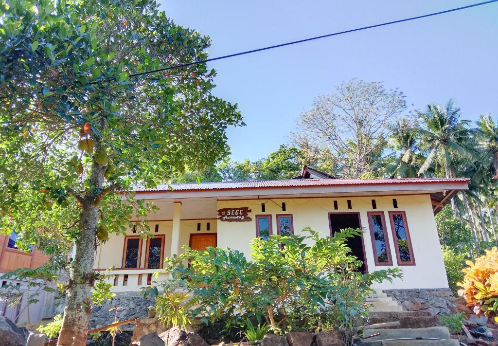 une maison jaune avec des arbres devant elle dans l'établissement SegeHomestay, à Rinondoran
