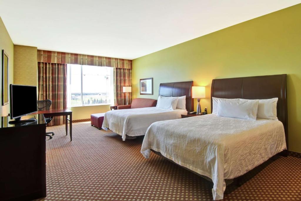 a hotel room with two beds and a flat screen tv at Hilton Garden Inn Ottawa Airport in Ottawa