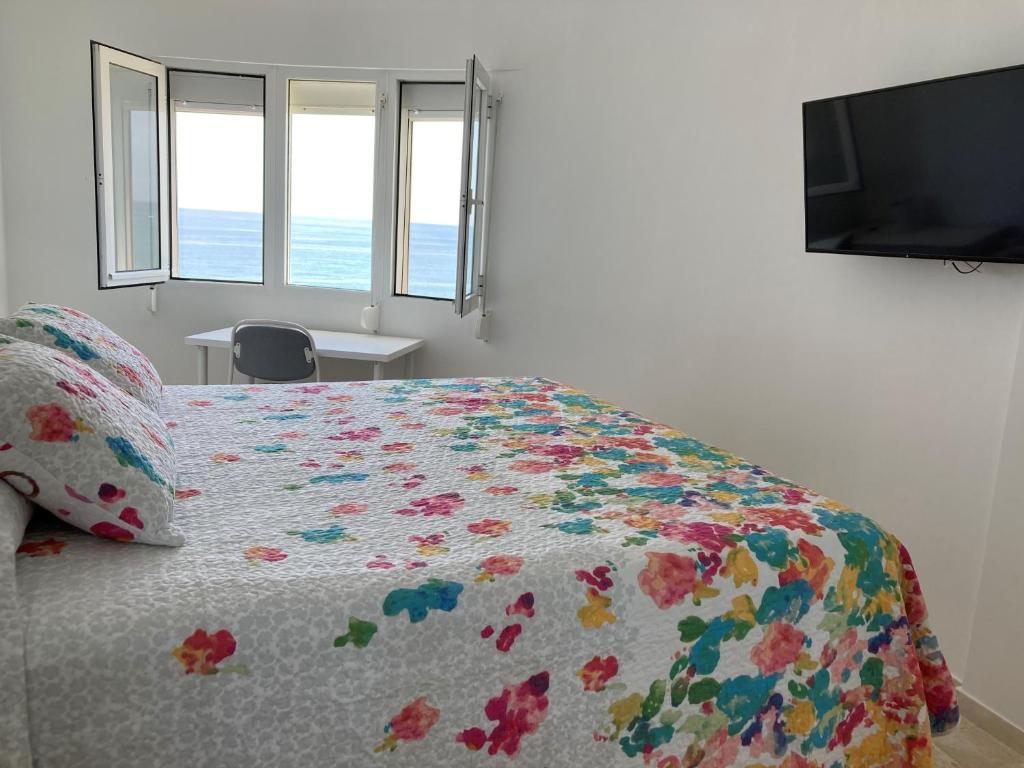 1 dormitorio con 1 cama con colcha de flores y TV en Apartamento SeaView en Sitio de Calahonda
