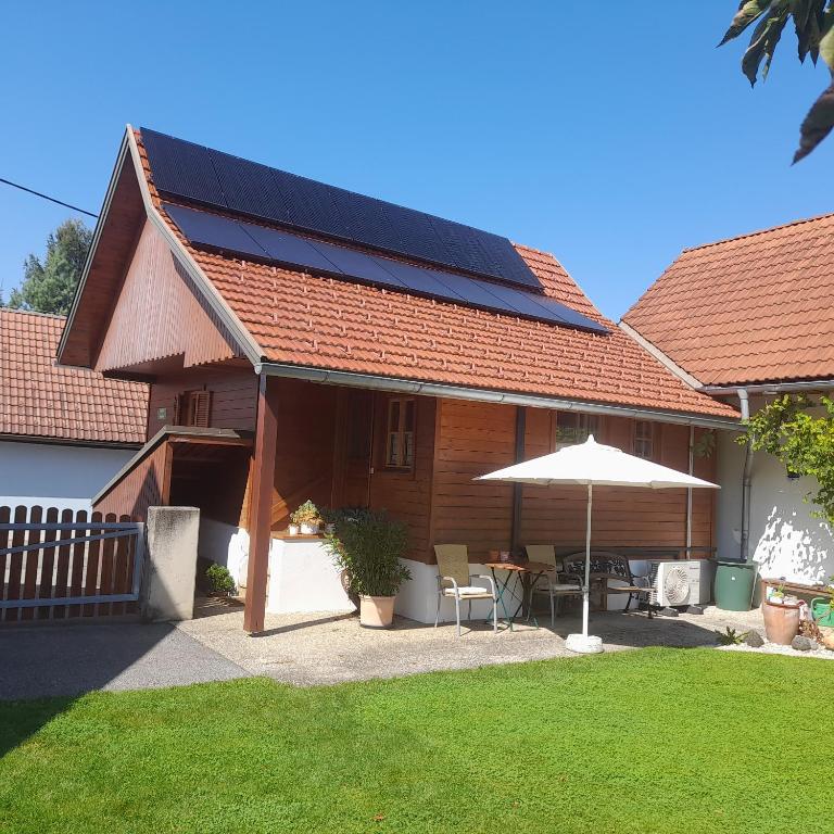 a house with a solar roof with a table and an umbrella at Kellerstöckl Maierjörgl in Sankt Martin im Sulmtal