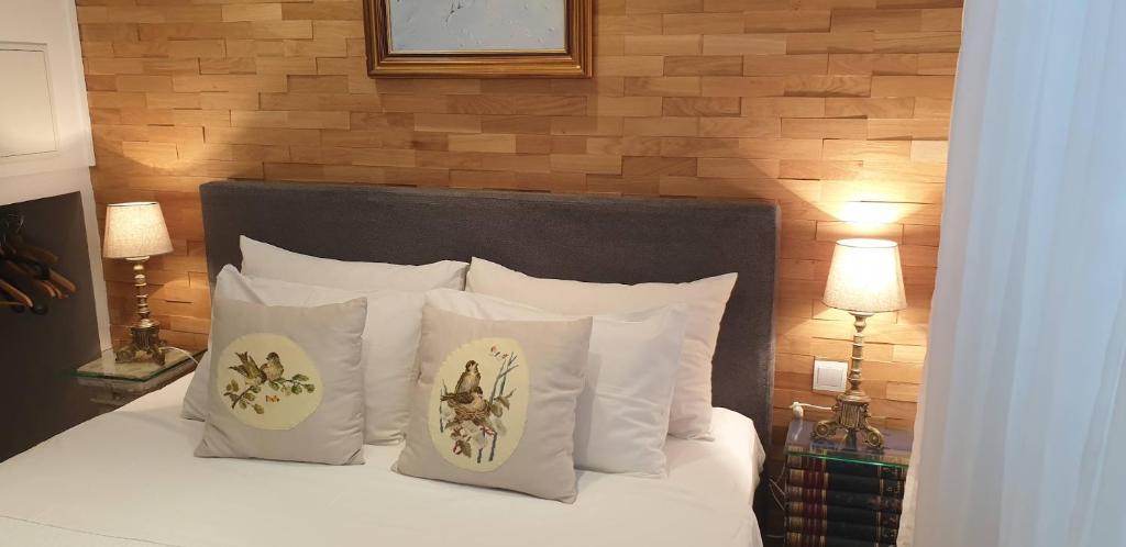 a bed with white pillows and a wooden wall at Apartment Mare s mora in Mokošica