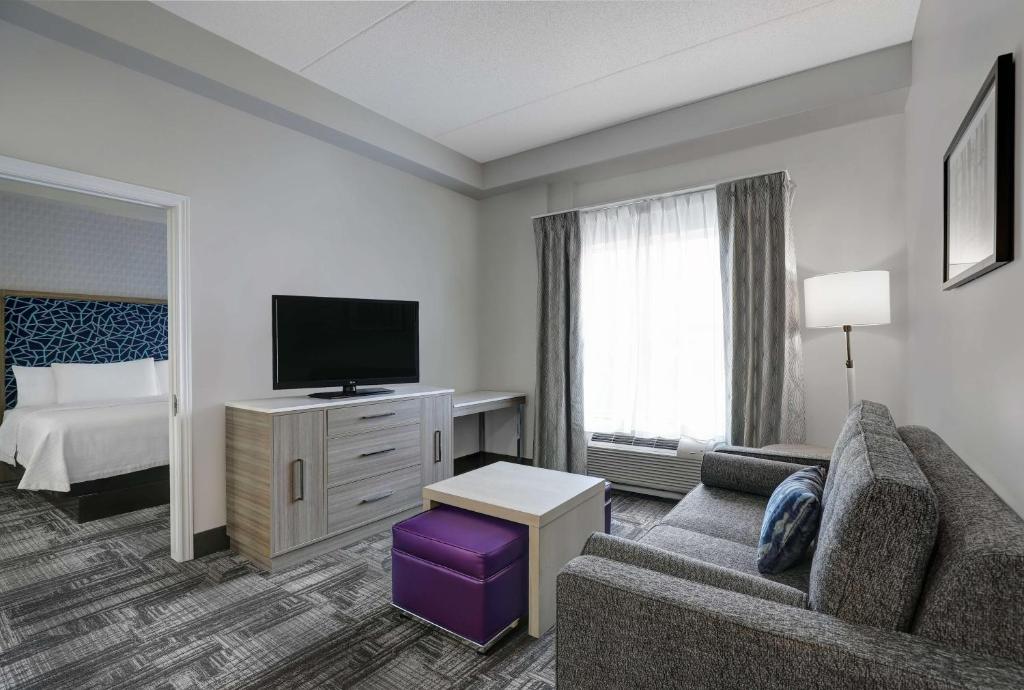 um quarto de hotel com um sofá, uma televisão e uma cama em Homewood Suites by Hilton London Ontario em London
