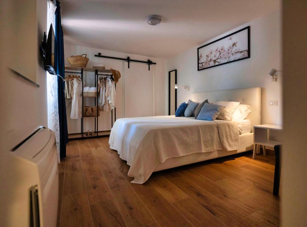 a bedroom with a white bed and a wooden floor at Diomira Apartment in Taormina
