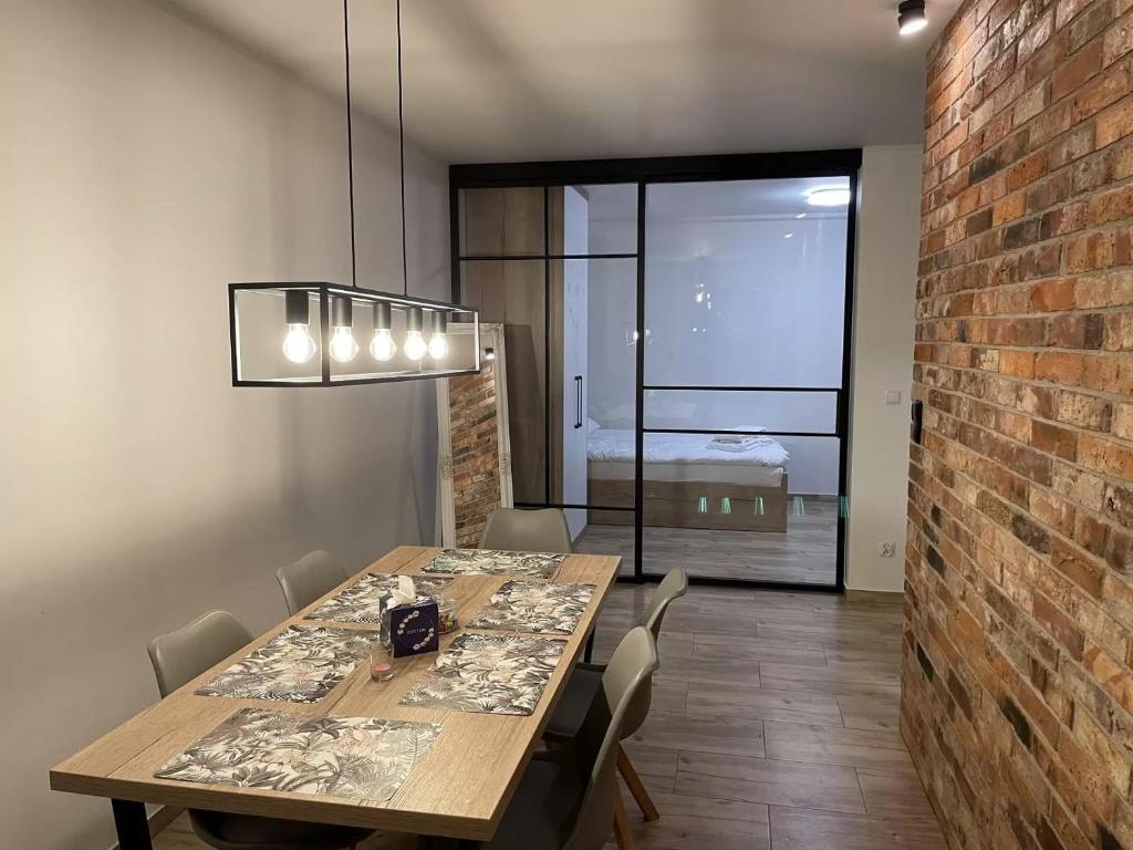 a dining room with a table and a brick wall at Apartament na Skarpie in Zator