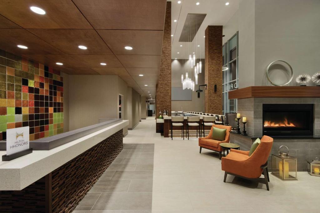 un hall avec une cheminée et des chaises ainsi qu'un restaurant dans l'établissement Hilton Garden Inn Calgary Downtown, à Calgary