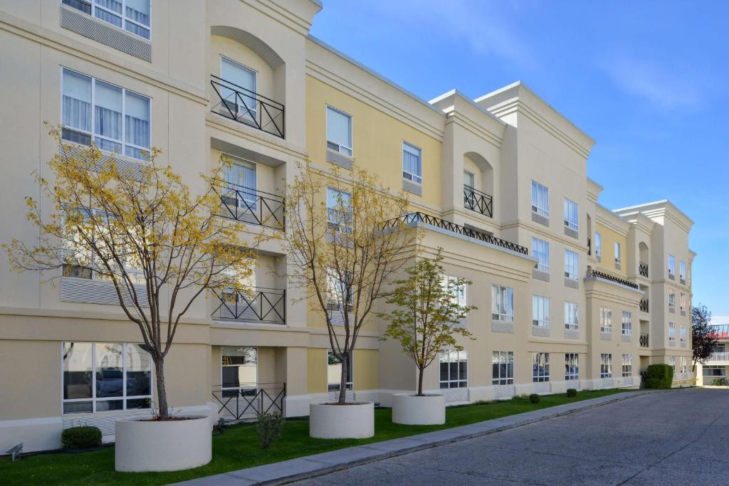 an apartment building with three trees in front of it at Hampton Inn & Suites by Hilton Calgary University NW in Calgary