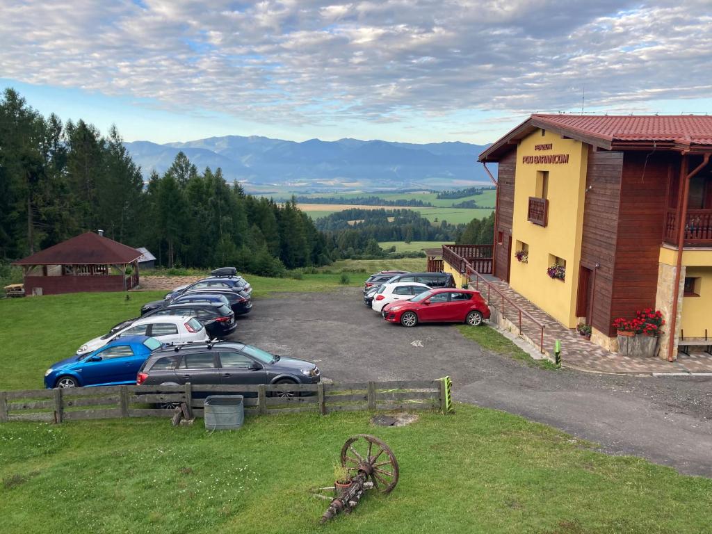 un gruppo di auto parcheggiate in un parcheggio accanto a un edificio di Penzión pod Barancom a Žiar