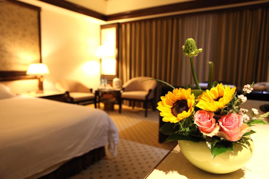 a hotel room with a vase of flowers on a table at King&#39;s Town Hotel in Kaohsiung