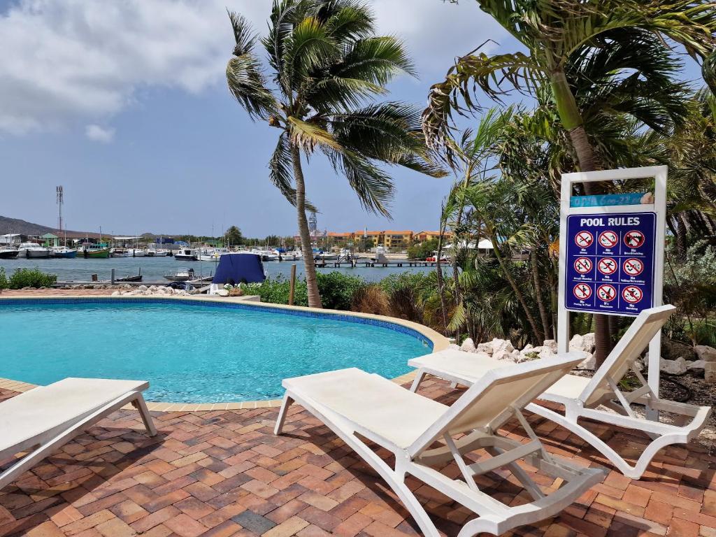 una piscina con due sedie a sdraio e un cartello accanto di Luxury appt for 6: mesmerizing Spanish water view a Jan Thiel