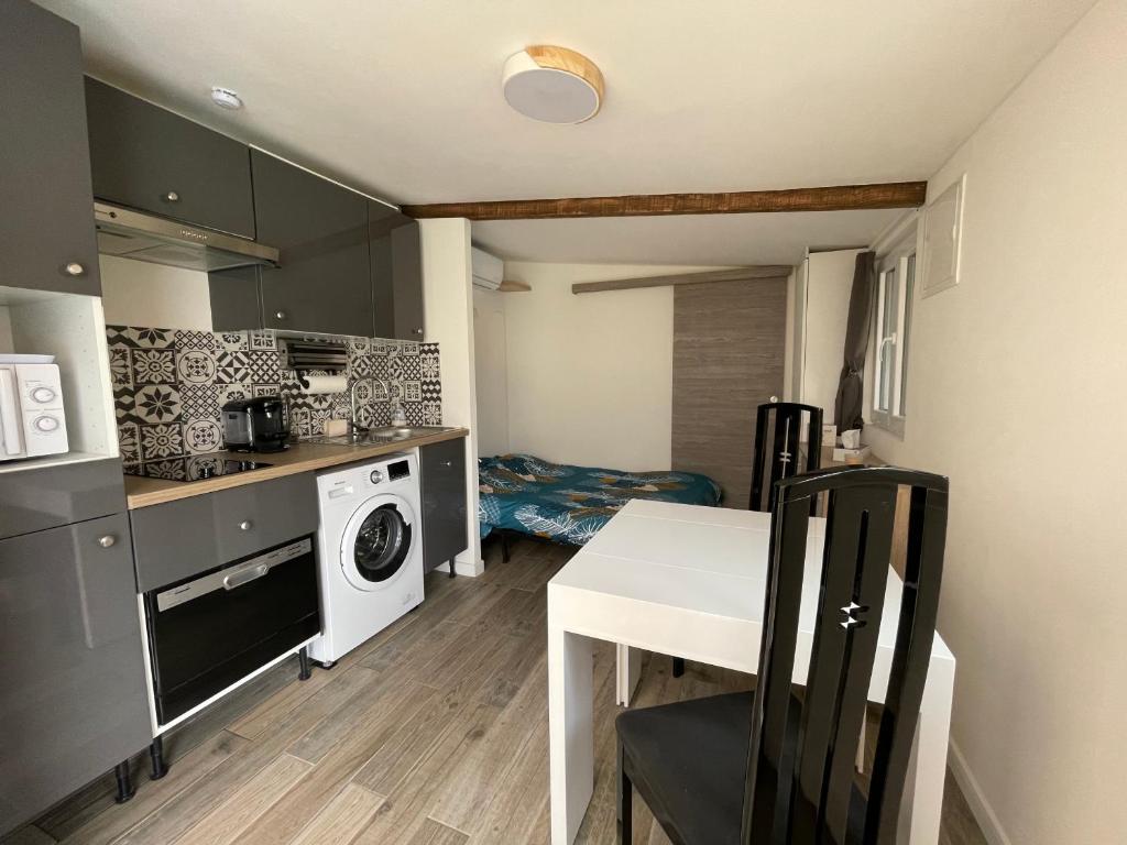 een kleine keuken met een tafel en een wasmachine bij Studio au calme climatisé avec terrasse in Paillet