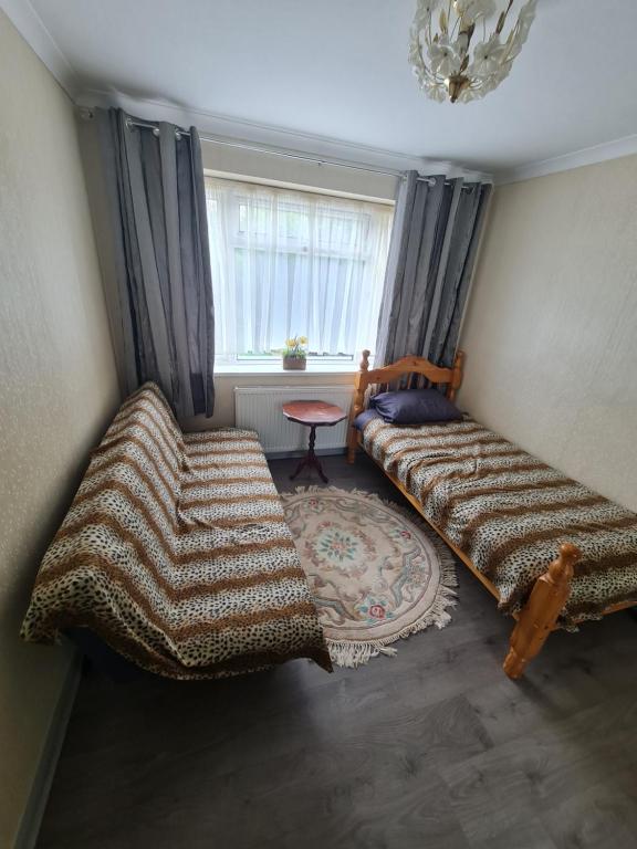 a living room with two beds and a window at Colne House in Yiewsley