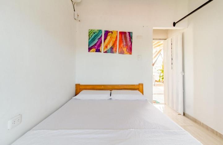 1 dormitorio con 1 cama blanca grande y una pintura en la pared en red moon, en Santa Marta