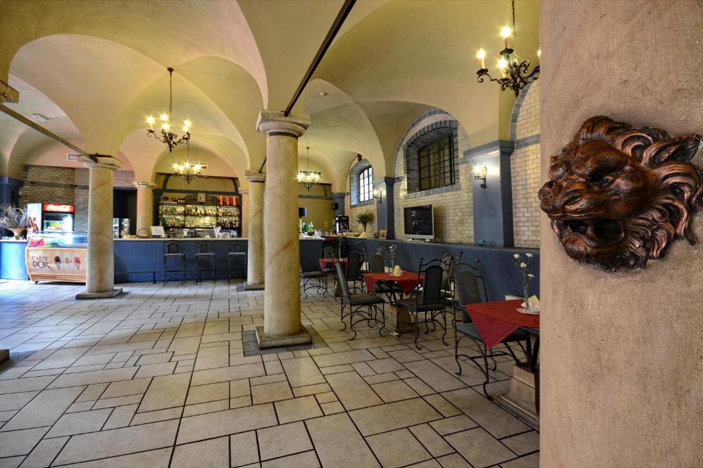 Cafe interior with stone columns, chandeliers, and a lion head wall decoration.