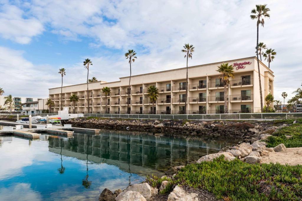 an exterior view of a hotel with palm trees at Hampton Inn Channel Islands Harbor in Oxnard