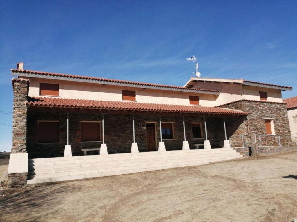 ceglany dom z białym płotem przed nim w obiekcie Albergue Villa de Salvatierra w mieście Salvatierra de Tormes