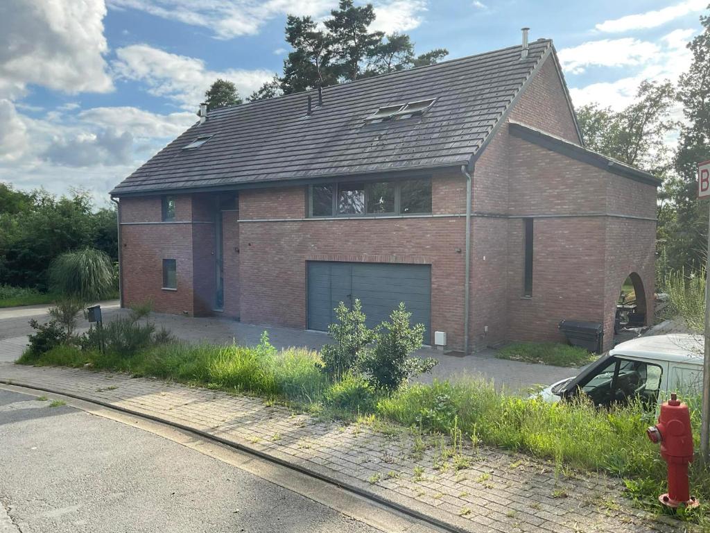 a brick house with a garage and a red fire hydrant at Le Petit Parc in Wavre