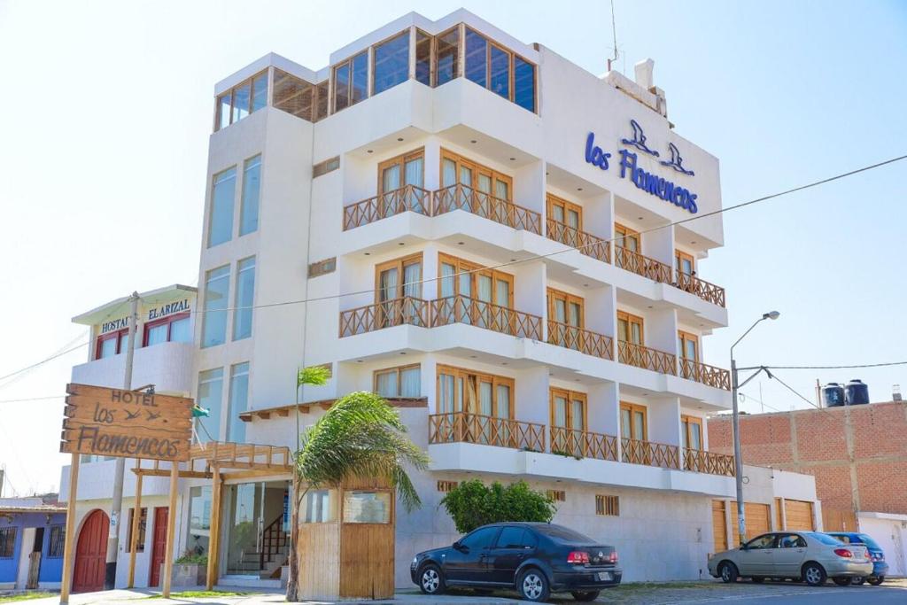 a white building with cars parked in front of it at Hotel Los Flamencos in Paracas