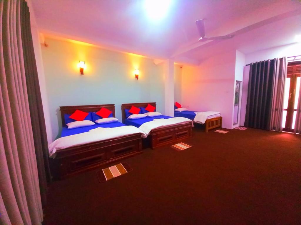 een slaapkamer met 2 bedden met blauwe en rode kussens bij Kithaya Ella in Ella