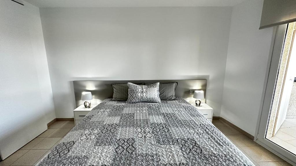 een slaapkamer met een groot bed met 2 nachtkastjes bij Apartamento con vistas a mar y canal. Empuriabrava in Empuriabrava
