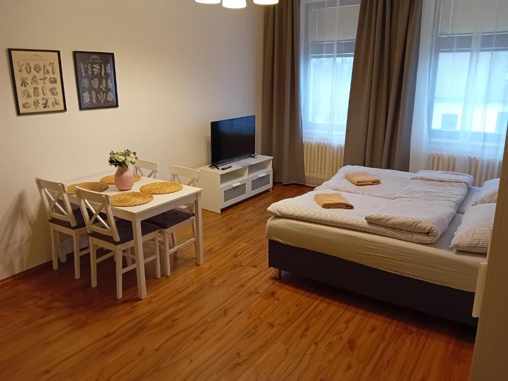 a bedroom with a bed and a table and a television at Apartmány Šrámek Stříbro in Stříbro