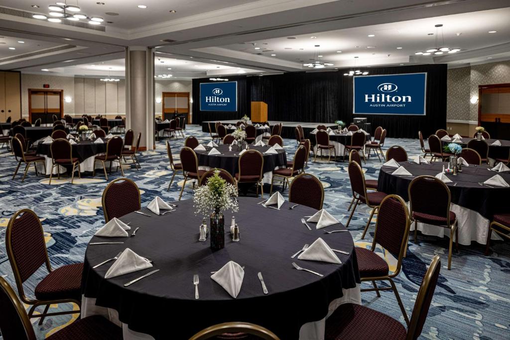 a conference room with tables and chairs and a stage at Hilton Austin Airport in Austin