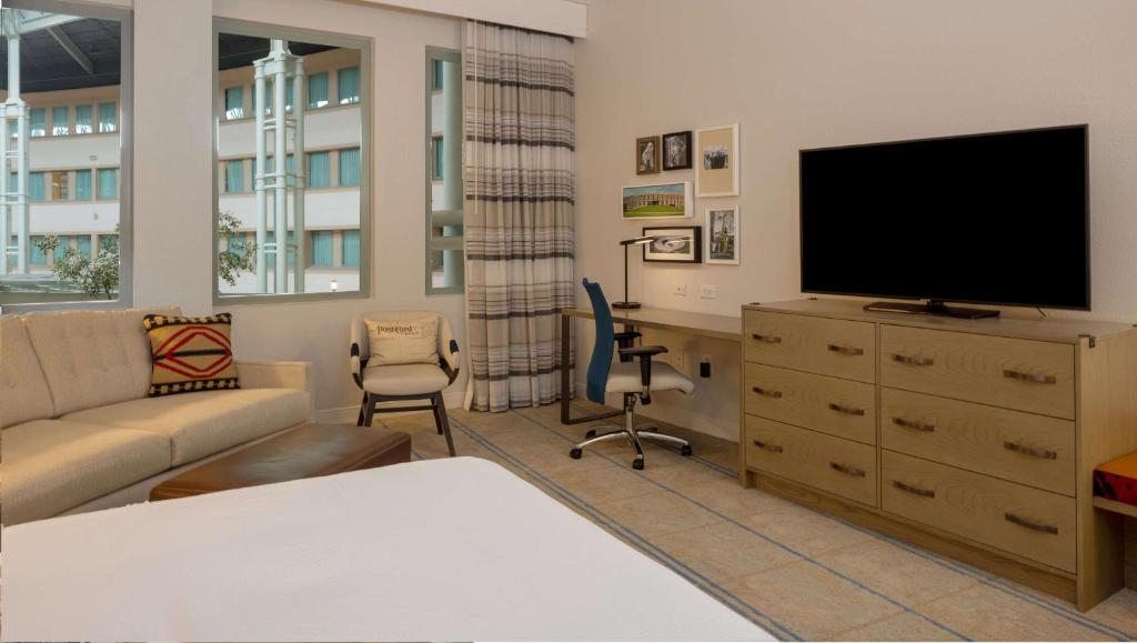 a living room with a tv and a couch and a desk at Hilton Austin Airport in Austin