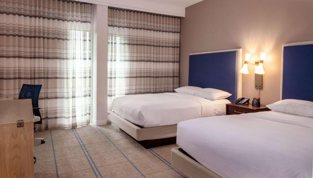 a hotel room with two beds and a window at Hilton Austin Airport in Austin