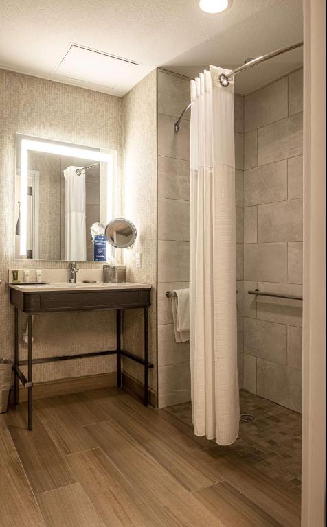 a bathroom with a sink and a mirror and a shower at Hilton Austin Airport in Austin