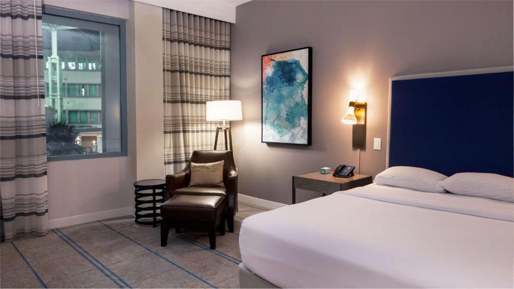 a bedroom with a bed and a chair and a window at Hilton Austin Airport in Austin