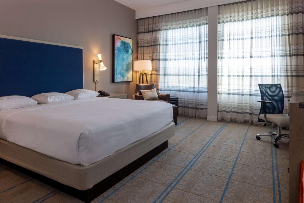a bedroom with a large bed and a desk and chair at Hilton Austin Airport in Austin