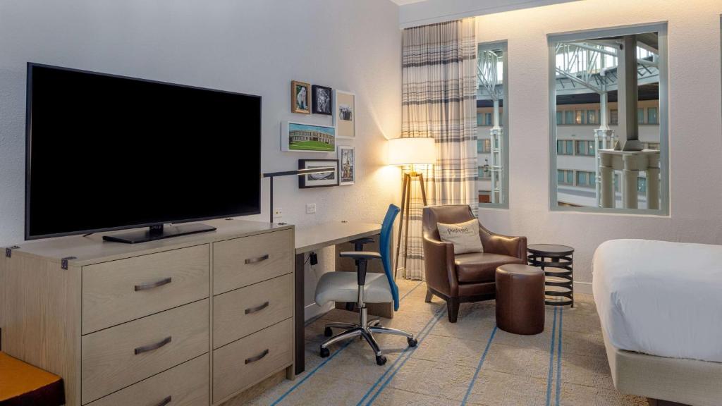 a bedroom with a desk with a television and a bed at Hilton Austin Airport in Austin
