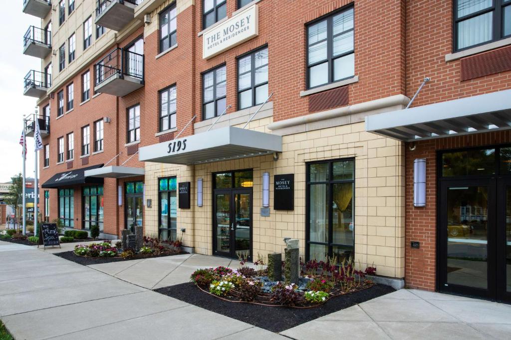 a brick building with flowers in front of it at The Mosey Buffalo Williamsville Tapestry Collection Hilton in Williamsville