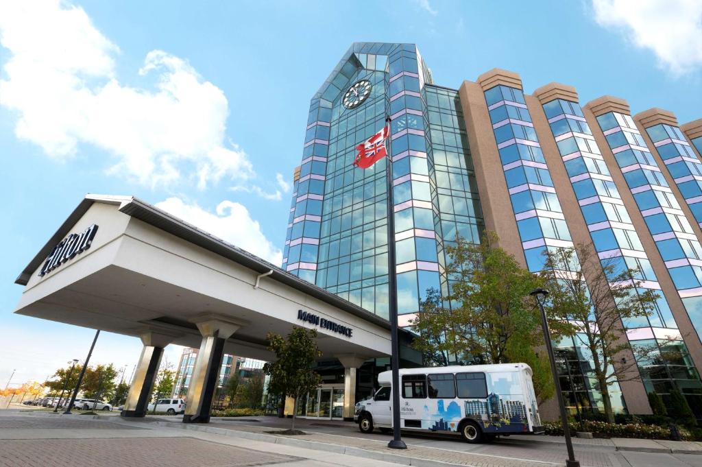 un autobús está estacionado frente a un edificio en Hilton Suites Toronto-Markham Conference Centre & Spa en Markham