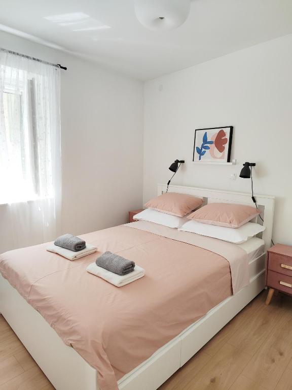 a white bedroom with a large bed with pink pillows at Apartment LIPA in Slatine