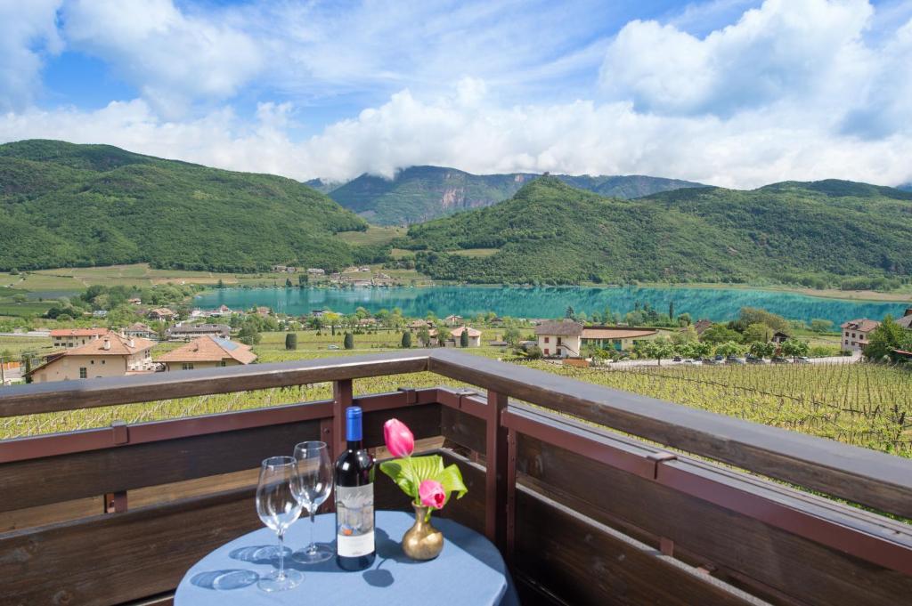 a table with wine glasses on a balcony with a view at Seeberg Garni Hotel in Caldaro