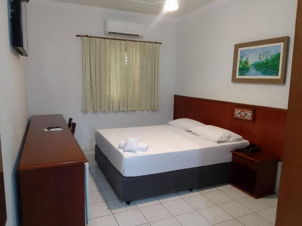 een kleine slaapkamer met een bed en een bureau bij Fênix Plaza Hotel in Aquidauana