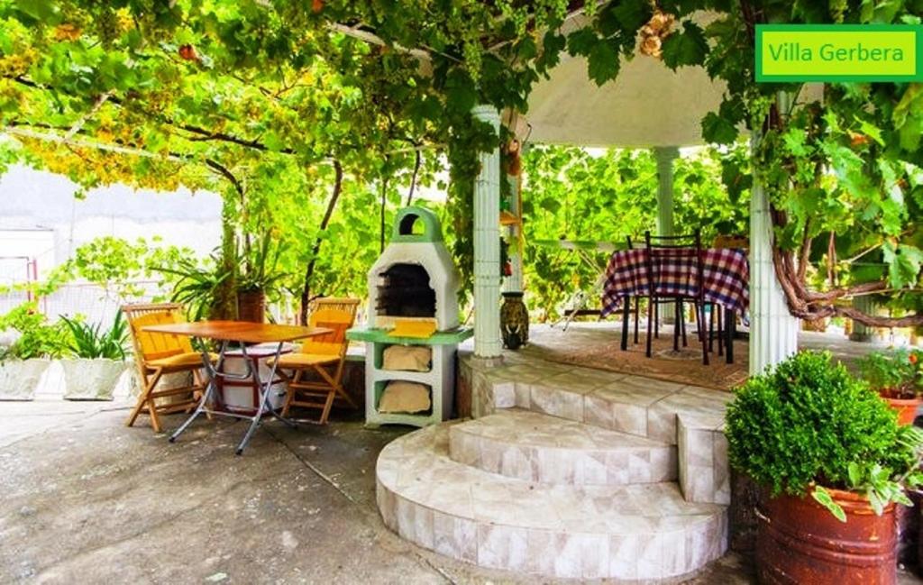 een patio met een tafel en stoelen en een fornuis bij Vila Gerbera in Sutomore