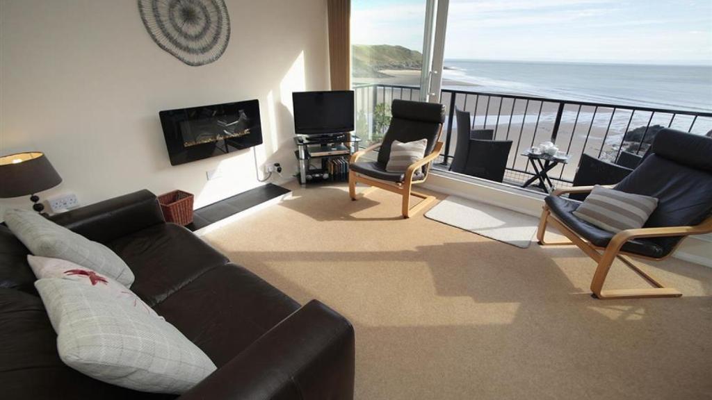 a living room with a couch and chairs and a balcony at 9_304 Redcliffe Apartments, Caswell Bay in Bishopston
