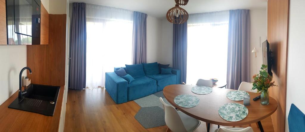 Apartament Rodzinny Sarbinowo في ساربينوفو: غرفة معيشة مع طاولة وأريكة زرقاء