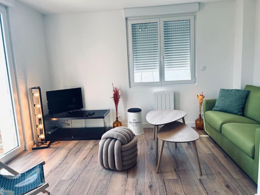 ein Wohnzimmer mit einem grünen Sofa und einem Tisch in der Unterkunft Au coeur des Chênes, 2p in Ploemeur