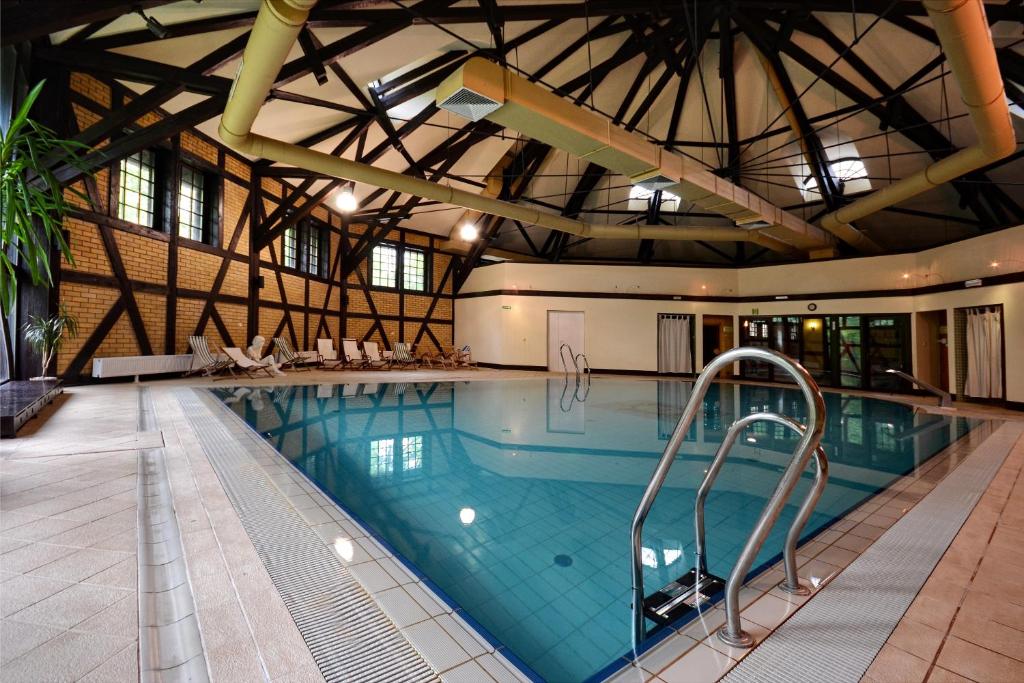Indoor swimming pool with wooden beams and lounge chairs.