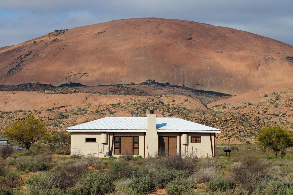 uma pequena casa branca em frente a uma montanha em Droëdap Guest Farm em Springbok
