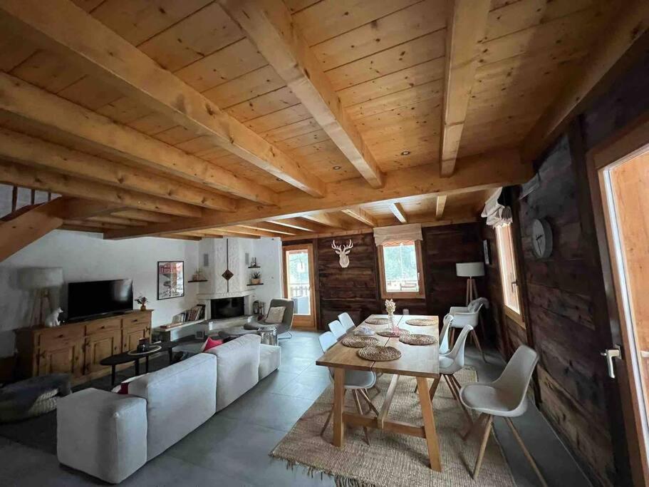 a living room with a wooden ceiling and a table and chairs at Châlet Champex-lac in Champex