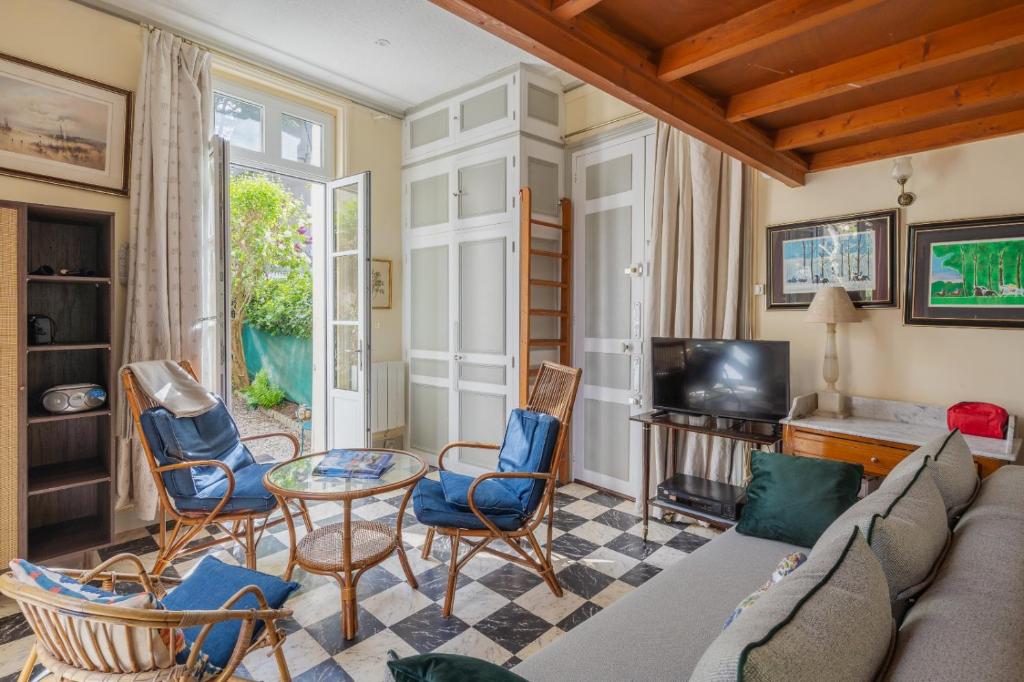 un salon avec un canapé, des chaises et une télévision dans l'établissement Studio de charme à Trouville sur mer., à Trouville-sur-Mer