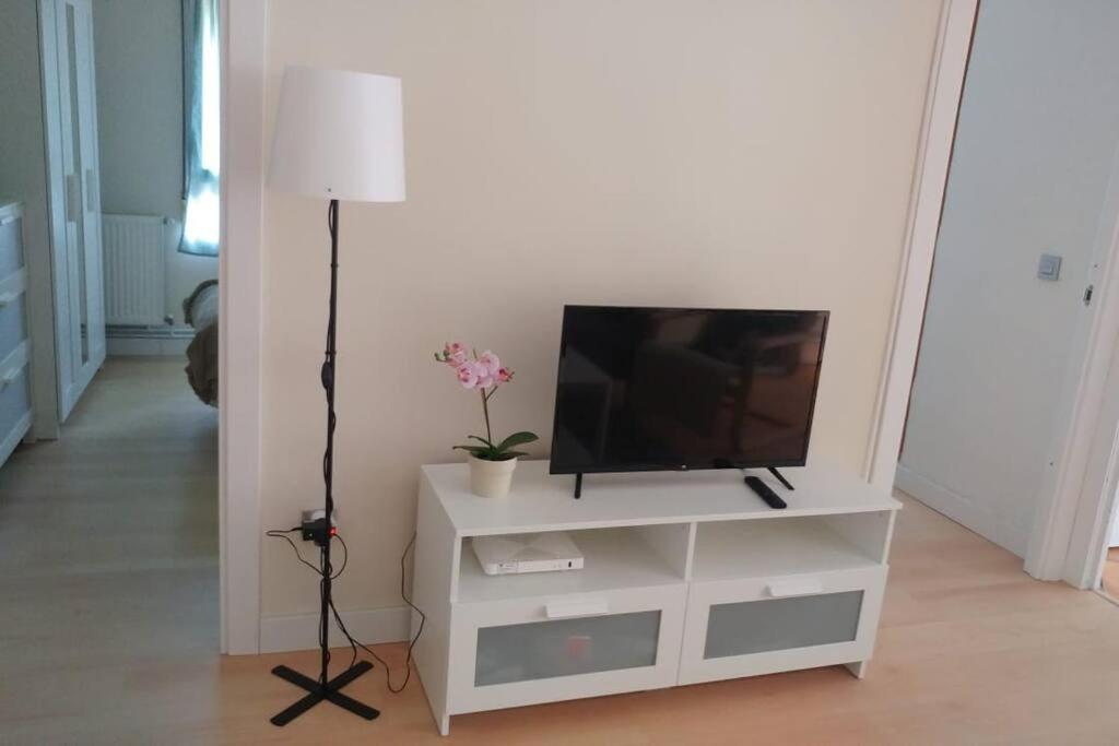 un centro de entretenimiento blanco con TV y lámpara en Bonito y acogedor apartamento cerca de Donostia San Sebastián en Lezo