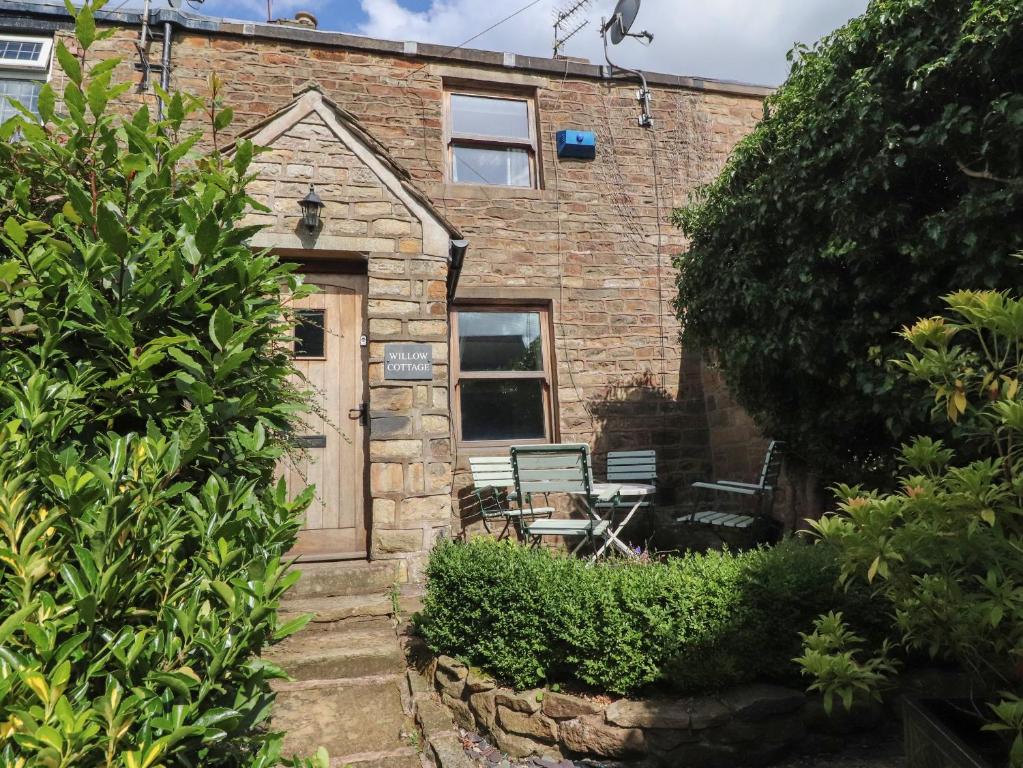 a brick house with a door and a bench at Willow Cottage in Clitheroe