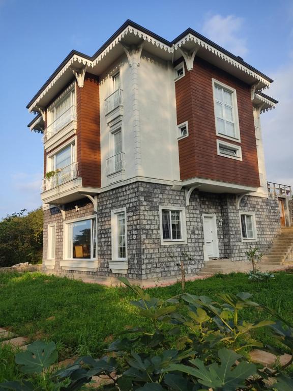 uma grande casa de tijolos no topo de um campo verde em Bahçeli villa dairesi em Trabzon